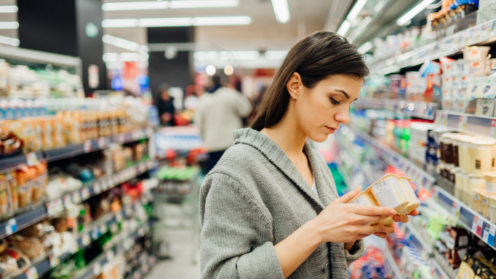 Anaemic woman in a shop checking a food product’s nutritional content 